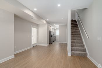 A spacious room with wooden floors and a staircase leading to another room.